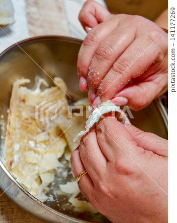 Hands deshelling salted cod for traditional cooking Hands deshelling salted cod for traditional cooking 141177269