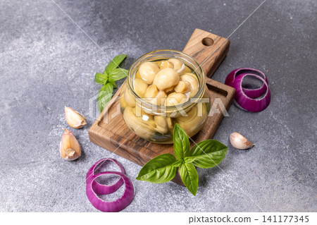 Pickled button mushrooms in jar on wooden board 141177345