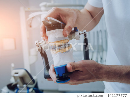 Dental technician working with articulator in dental lab Dental technician working with articulator in dental lab 141177777