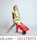 Little girl with wheelbarrow on the white background. Construction 141178373