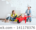 Little girl and boy with wheelbarrow on the white background. Construction 141178376