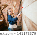 Little girl in a room with a wooden wall. Construction 141178379