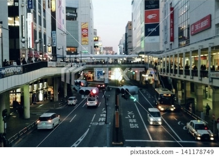 黃昏前，車站前車輛和行人來來往往。城市燈光逐漸照亮了都市景觀。 141178749
