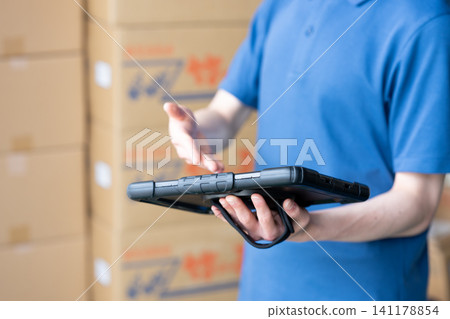 A man's hands using a tablet in a warehouse A man's hands using a tablet in a warehouse 141178854
