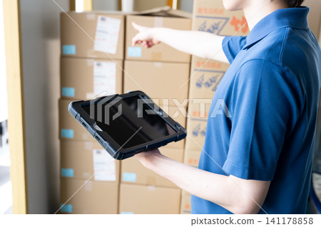 A man's hands using a tablet in a warehouse A man's hands using a tablet in a warehouse 141178858