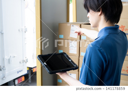 A man's hands using a tablet in a warehouse A man's hands using a tablet in a warehouse 141178859