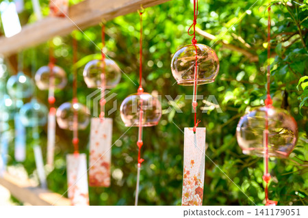 A cool wind chime shining in the sunlight filtering through the trees A cool wind chime shining in the sunlight filtering through the trees 141179051