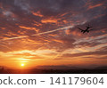 Airplane flying in the sunset sky 141179604