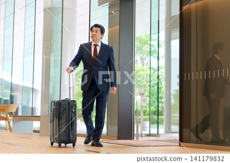 Asian businessman walking with a suitcase Asian businessman walking with a suitcase 141179832