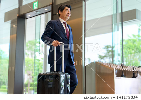 Asian businessman walking with a suitcase Asian businessman walking with a suitcase 141179834