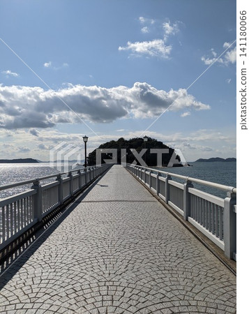 通往島嶼的鵝卵石橋,配有白色欄桿,從一點視角可以眺望藍天和大海。 通往島嶼的鵝卵石橋,配有白色欄桿,從一點視角可以眺望藍天和大海。 141180066
