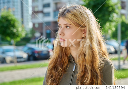 Thoughtful young blonde woman looking away on a modern city street Thoughtful young blonde woman looking away on a modern city street 141180394