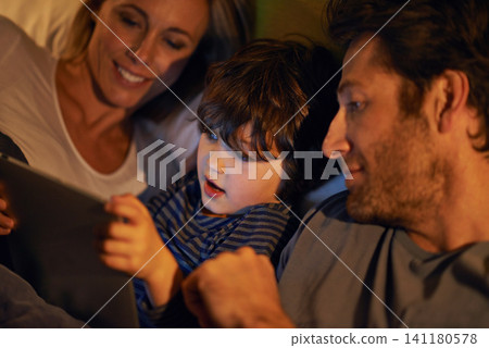 Bed, parents or kid with tablet for streaming, playing games or watching videos on movie website in home. Social media, child or happy mom with dad or technology to download on ebook online at night Bed, parents or kid with tablet for streaming, playing games or watching videos on movie website in home. Social media, child or happy mom with dad or technology to download on ebook online at night 141180578