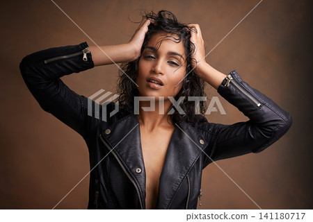 Woman, fashion and portrait in studio with leather jacket and beauty with makeup for bold, and chic. Indian person, model and edgy with curls and clothes for aesthetic and style for trend and cool Woman, fashion and portrait in studio with leather jacket and beauty with makeup for bold, and chic. Indian person, model and edgy with curls and clothes for aesthetic and style for trend and cool 141180717