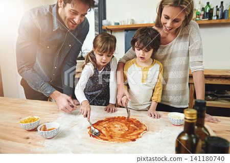 Parents, kids and happy for cooking pizza with sauce, learning and helping hand for development in kitchen. Mother, father and children with dough, teaching and support with bonding in family house Parents, kids and happy for cooking pizza with sauce, learning and helping hand for development in kitchen. Mother, father and children with dough, teaching and support with bonding in family house 141180740