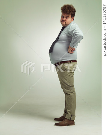 Business man, portrait and plus size with unhappy, sad and frustrated in studio with arms on hips. Job, employee and office fashion with problem and clothing with green background and moody from work Business man, portrait and plus size with unhappy, sad and frustrated in studio with arms on hips. Job, employee and office fashion with problem and clothing with green background and moody from work 141180797