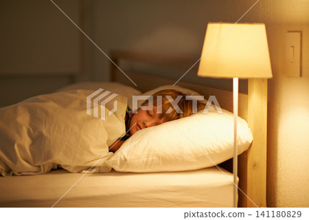 Boy, bed and rest for night, sleeping and tired with fatigue and peace. Child, dreaming and exhausted with pyjamas, blanket and bedroom with lamp for serene childhood at home or house for calm kid Boy, bed and rest for night, sleeping and tired with fatigue and peace. Child, dreaming and exhausted with pyjamas, blanket and bedroom with lamp for serene childhood at home or house for calm kid 141180829