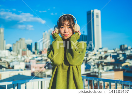 A smiling woman wearing earmuffs under a blue sky A smiling woman wearing earmuffs under a blue sky 141181497