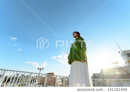 一位女子凝視著沐浴在陽光下的城市景觀。 141181498