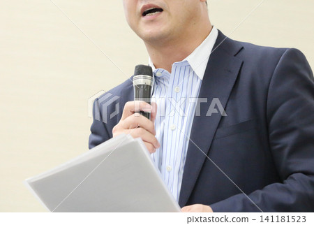 一名身穿西裝的男子手持麥克風講話,鏡頭對準了他的嘴巴和上半身;一名商人對著麥克風講話。 一名身穿西裝的男子手持麥克風講話,鏡頭對準了他的嘴巴和上半身;一名商人對著麥克風講話。 141181523