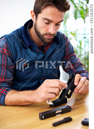 Process, cleaning and man with gun at table for safety, self defense and confident handgun assembly. Caution, equipment and person with firearm maintenance, cloth and wiping dust, dirt and tools Process, cleaning and man with gun at table for safety, self defense and confident handgun assembly. Caution, equipment and person with firearm maintenance, cloth and wiping dust, dirt and tools 141181672