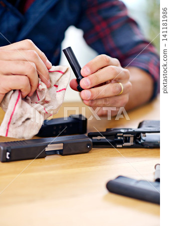 Hands, cleaning and man with firearm at table for safety, self defense and handgun assembly. Process, equipment and person with gun maintenance with cloth, magazine and wiping dust, dirt and oil Hands, cleaning and man with firearm at table for safety, self defense and handgun assembly. Process, equipment and person with gun maintenance with cloth, magazine and wiping dust, dirt and oil 141181986