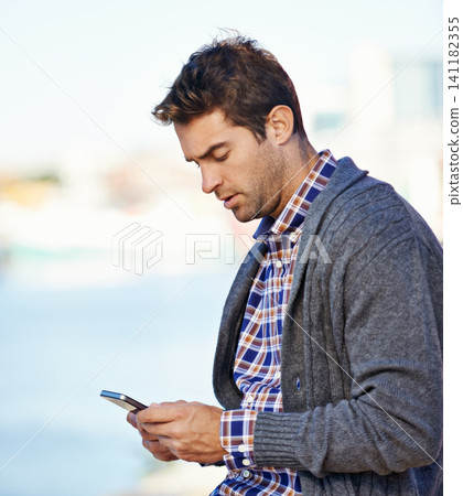 Man, phone and texting at harbor on mobile network by sea for typing, contact or reading outdoor. Person, smartphone and click at urban port in city for notification, app or social media in Cape Town 141182355