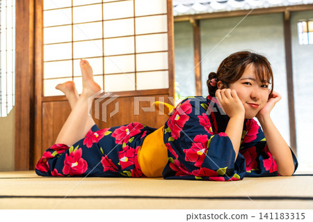 一位身穿浴衣的女子在日式房間消磨時光。 一位身穿浴衣的女子在日式房間消磨時光。 141183315