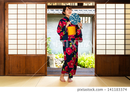 一位身穿浴衣的女子在日式房間消磨時光。 一位身穿浴衣的女子在日式房間消磨時光。 141183374