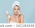 Woman uses facial product in bath towel 141183438