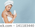 Relaxed woman in towel, holding product, gentle expression 141183440