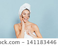 Smiling woman with face mask and towel, light blue background 141183446