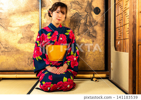 一位身穿浴衣的女子在日式房間消磨時光。 一位身穿浴衣的女子在日式房間消磨時光。 141183539