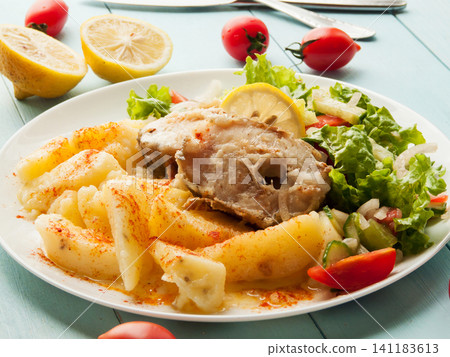 Juicy fried seafood pollock fish steaks with boiled potatoes and tomatoes lettuce onion salad 141183613