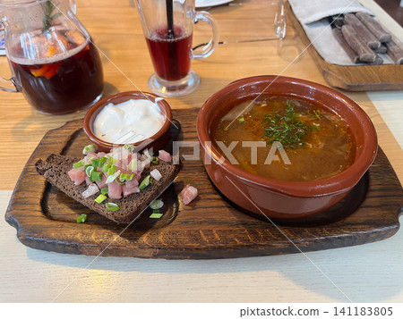 Traditional Ukrainian borscht beet soup served in a clay bowl with sour cream lard and dark rye bread on a wooden board Traditional Ukrainian borscht beet soup served in a clay bowl with sour cream lard and dark rye bread on a wooden board 141183805