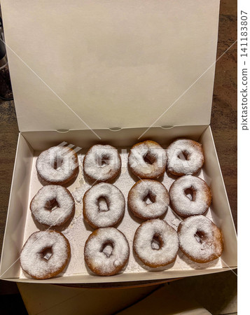 Fresh donuts with powdered sugar inside a white cardboard delivery box Fresh donuts with powdered sugar inside a white cardboard delivery box 141183807