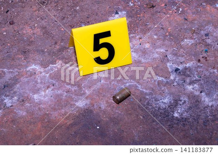 Bullet Casing with Yellow Evidence Marker Number 5 at Crime Scene Bullet Casing with Yellow Evidence Marker Number 5 at Crime Scene 141183877