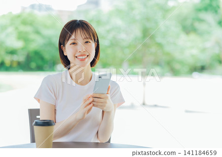 A young woman with short hair holding a smartphone A young woman with short hair holding a smartphone 141184659