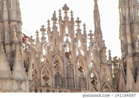 Gothic Architecture Detail of Milan Cathedral with Intricate Spires and Stone Carvings. Duomo di Milano Gothic Architecture Detail of Milan Cathedral with Intricate Spires and Stone Carvings. Duomo di Milano 141184897
