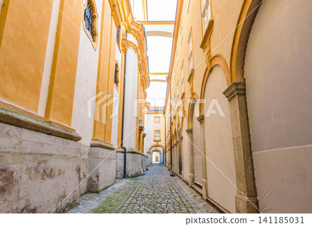 A cobblestone alley nestled between the yellow buildings of Melk Abbey, a UNESCO World Heritage Site and part of the Wachau Valley Cultural Landscape. A cobblestone alley nestled between the yellow buildings of Melk Abbey, a UNESCO World Heritage Site and part of the Wachau Valley Cultural Landscape. 141185031