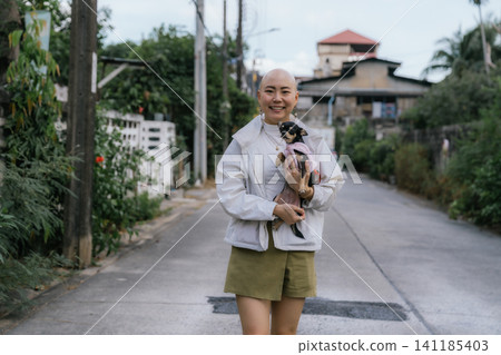 Bald woman smiling holding chihuahua on street Bald woman smiling holding chihuahua on street 141185403