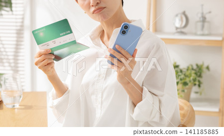 A middle-aged woman looking at her bankbook and worrying A middle-aged woman looking at her bankbook and worrying 141185885