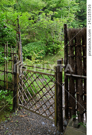 A traditional bamboo gate stands amidst a lush garden; a simple wooden and bamboo gate, harmonizing with nature, invites you down a charming Japanese garden path. A traditional bamboo gate stands amidst a lush garden; a simple wooden and bamboo gate, harmonizing with nature, invites you down a charming Japanese garden path. 141185916