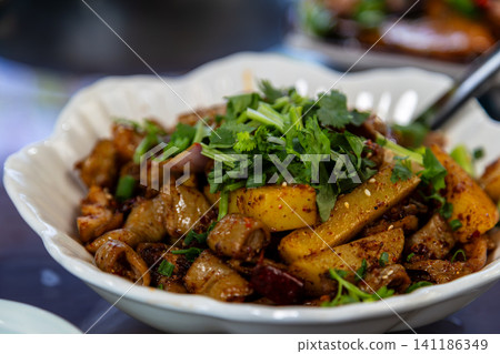 A close-up of a local dish from Dali, Yunnan: a dry pot dish featuring pork intestines, cilantro, potatoes, chili peppers, and spices. 141186349