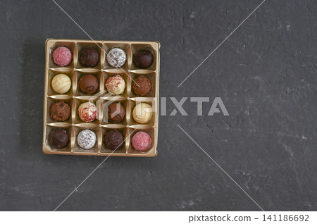Chocolate candies arranged in square box on dark background. Chocolate candies arranged in square box on dark background. 141186692