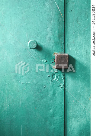 Square lock sits on painted iron background in corridor. Square lock sits on painted iron background in corridor. 141186834