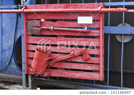 Bright safety shield holds classic rescue gear on slatted wall panel. Bright safety shield holds classic rescue gear on slatted wall panel. 141186897