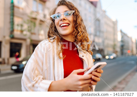 Happy woman tourist with phone. Young woman writing text for sharing content about vacations Happy woman tourist with phone. Young woman writing text for sharing content about vacations 141187027
