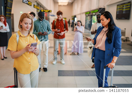Travelers waiting in airport terminal using smartphones Travelers waiting in airport terminal using smartphones 141187055