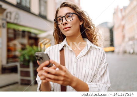 Young woman with phone on the street. Technology, blogging, communication concept. Young woman with phone on the street. Technology, blogging, communication concept. 141187534